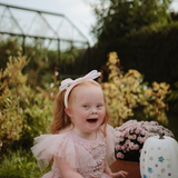 Laughing girl in a pink dress at a garden table with the Mushie Fairies Reusable Water Color Pad