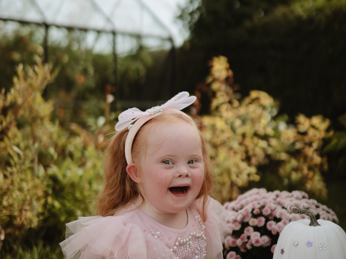 Laughing girl in a pink dress at a garden table with the Mushie Fairies Reusable Water Color Pad