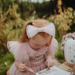 Girl with a pink bow painting on the Mushie Fairies Reusable Water Color Pad outdoors