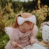 Girl with a pink bow painting on the Mushie Fairies Reusable Water Color Pad outdoors