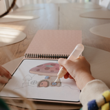 Close-up of a child's hand painting a mushroom fairy house on the Mushie Fairies Reusable Water Color Pad