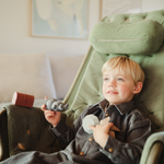 Boy in a green armchair playing with the Mushie Mold Free Bath Play Set Pirate toys