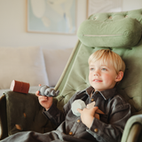 Boy in a green armchair playing with the Mushie Mold Free Bath Play Set Pirate toys