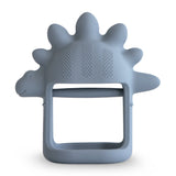Mushie No-Drop Dino Teether, a slate blue silicone stegosaurus-shaped teether with a wrist loop