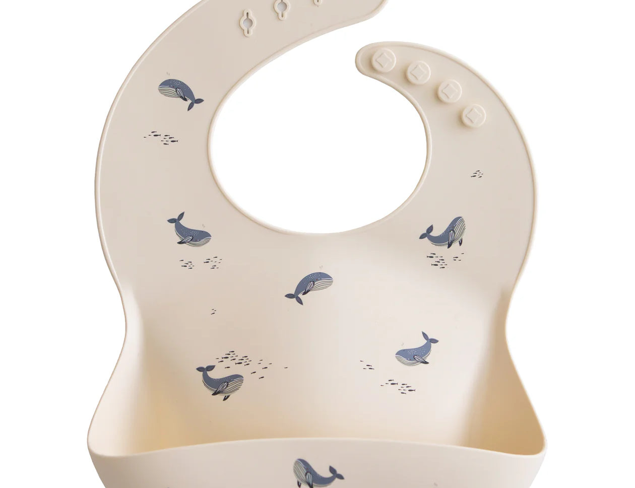 Mushie Silicone Baby Bib in Whales, a cream bib with a blue whale print and a catch pocket