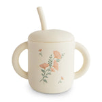 Mushie Silicone Training Cup + Straw in Pink Flowers, a cream cup with two handles, a lid and a straw