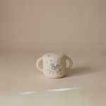 Mushie Snack Cup in Bluey Ivory on a neutral surface in soft light