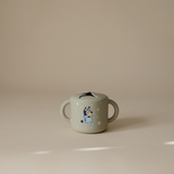 Mushie Snack Cup in Bluey Sage on a neutral surface in soft light
