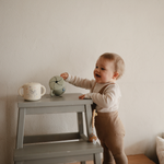 Toddler reaching for a Mushie Snack Cup in Bluey Sage on a step stool