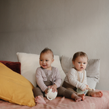 Two toddlers sitting on a bed with Mushie Snack Cups in Bluey prints