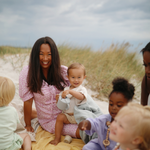 Group of mothers and children with Mushie Snack Cups sitting on a beach