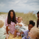 Group of mothers and children with Mushie Snack Cups sitting on a beach