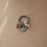 Mushie Space Teething Ring on a tan surface in soft light