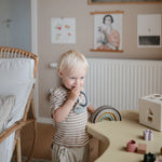 Toddler chewing the Mushie Space Teething Ring in a playroom