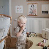 Toddler chewing the Mushie Space Teething Ring in a playroom