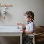 Toddler at a white table playing with the Mushie Sunshine Suction Spinner Toy