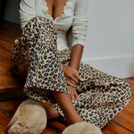 Woman in leopard pants sitting on the floor wearing Nude Snowball Slippers in Camel