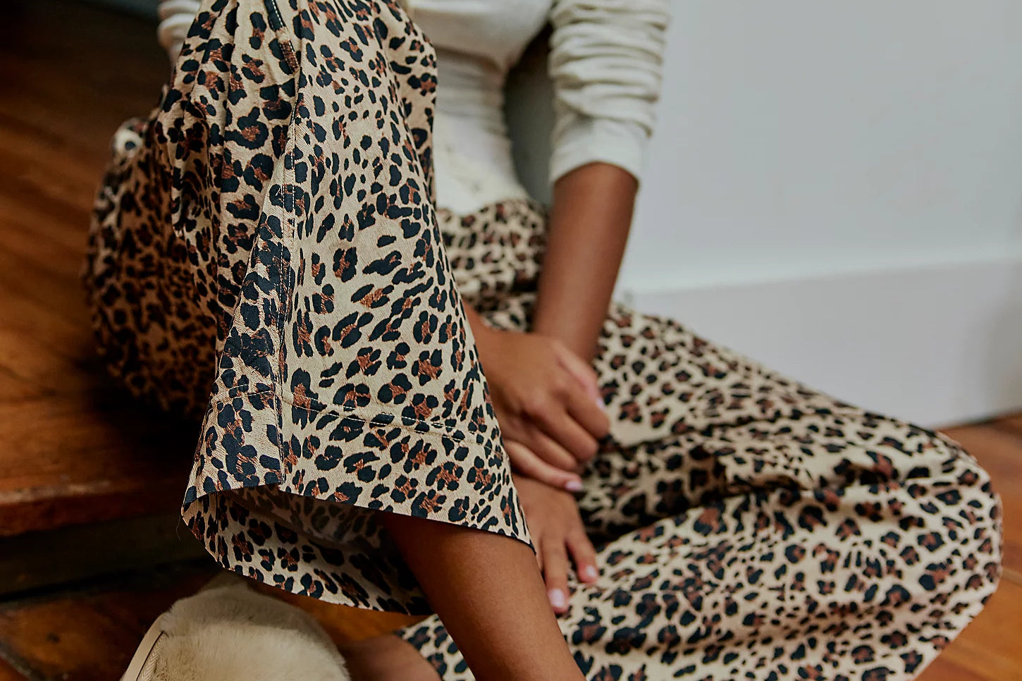Woman in leopard pants sitting on the floor wearing Nude Snowball Slippers in Camel