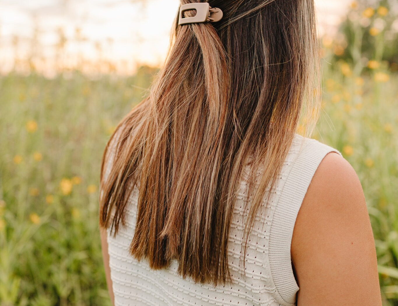 The Beige oval lay flat matte claw clip holding a half up style, sitting flat against the back of the head.