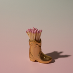 Paddywax Cowboy Boot Match Holder in Gold Metallic with matches on a pink background