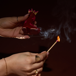 Hands striking a match on the red Paddywax Cowboy Boot Match Holder in a dark room