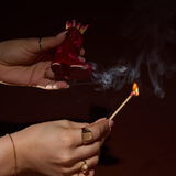 Hands striking a match on the red Paddywax Cowboy Boot Match Holder in a dark room