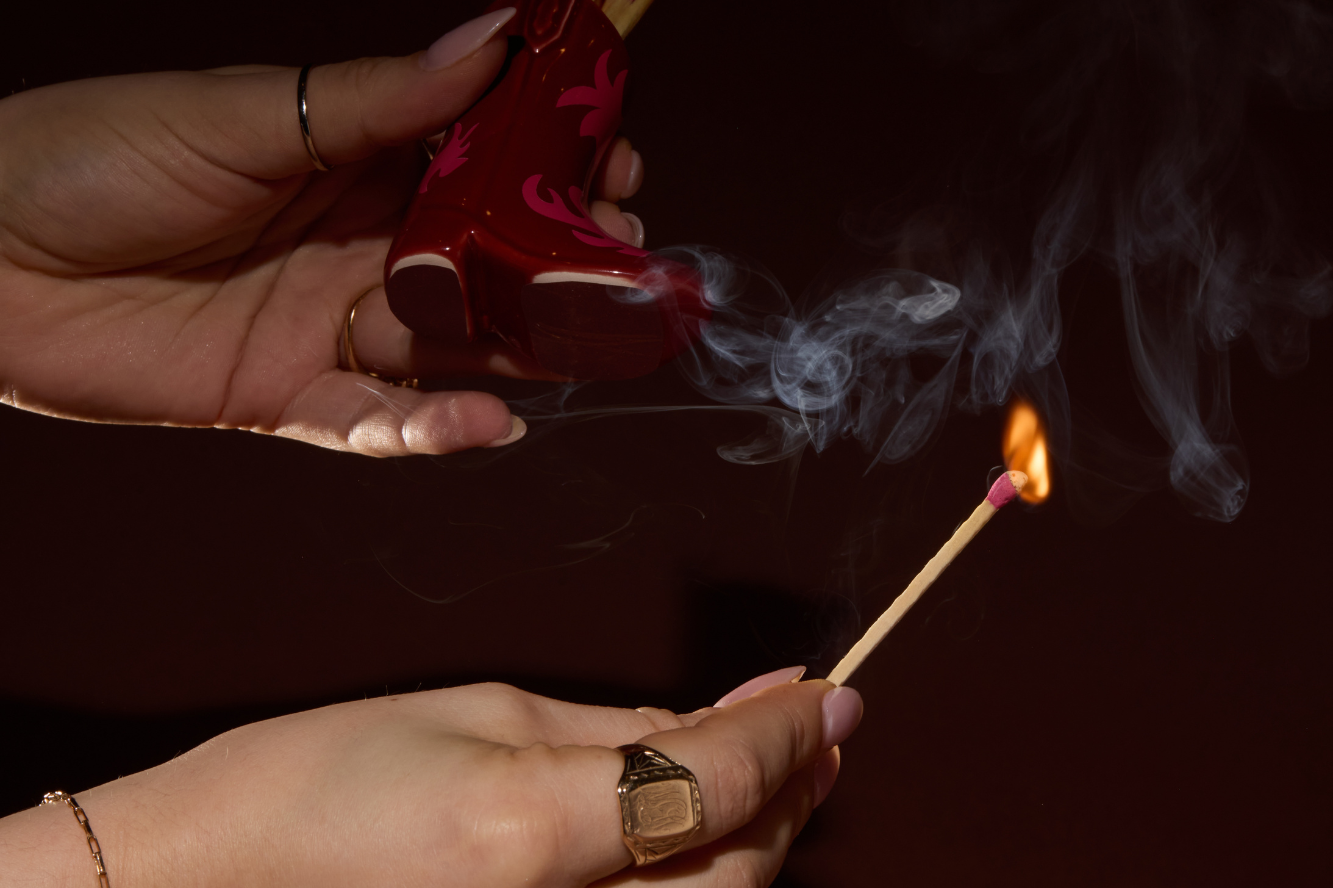 Hands striking a match on the red Paddywax Cowboy Boot Match Holder in a dark room