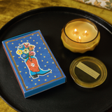 Cobalt blue Paddywax matchbox with a cowboy boot holding flowers and gold stars