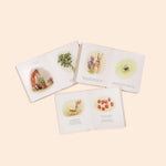 Paige Tate & Co Our Little Adventures board books open to watercolor pages of animals and plants