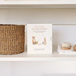 Paige Tate & Co Our Little Adventures Box Set on a white shelf beside a woven basket