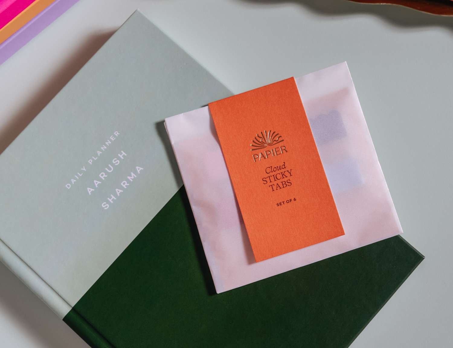 Papier Cloud Sticky Index Tabs in an orange packet resting on a green notebook