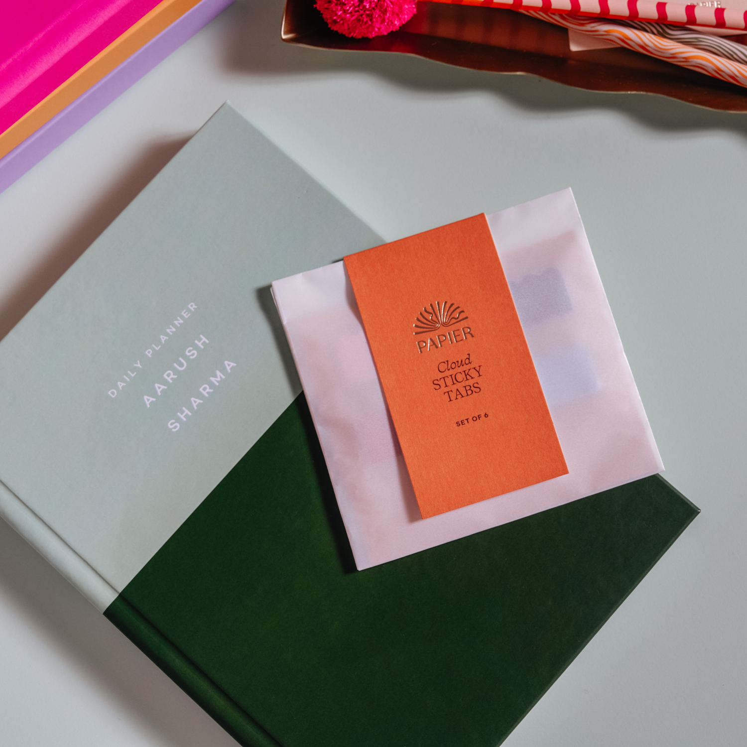 Papier Cloud Sticky Index Tabs in an orange packet resting on a green notebook