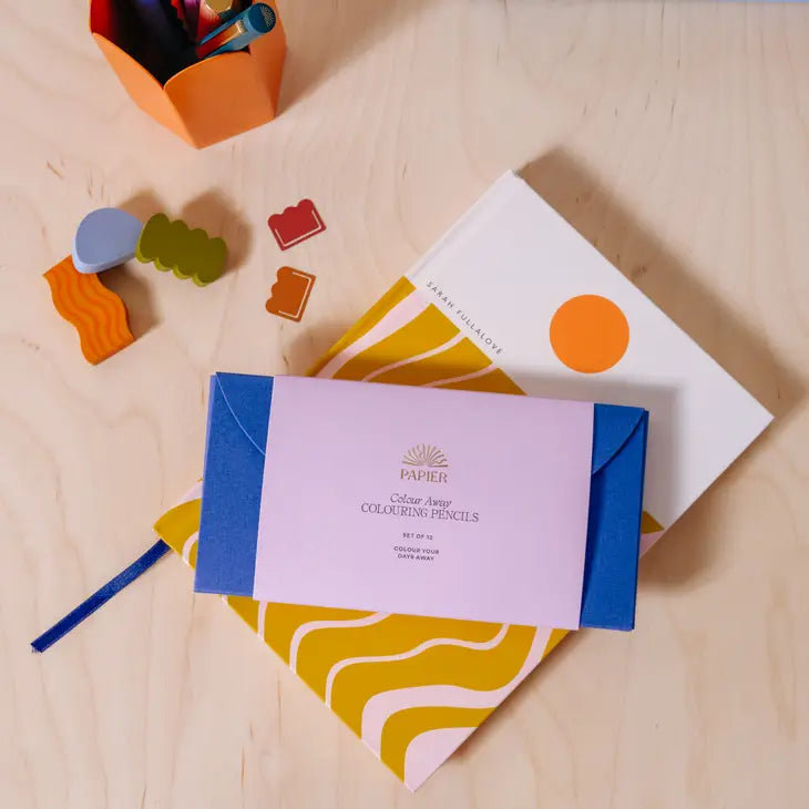 Papier Color Away Coloring Pencil Set of 12 in its lilac and blue box on a desk with notebooks
