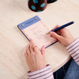 Hand writing on the Papier Fabric Hardcover Notepad in pink at a desk