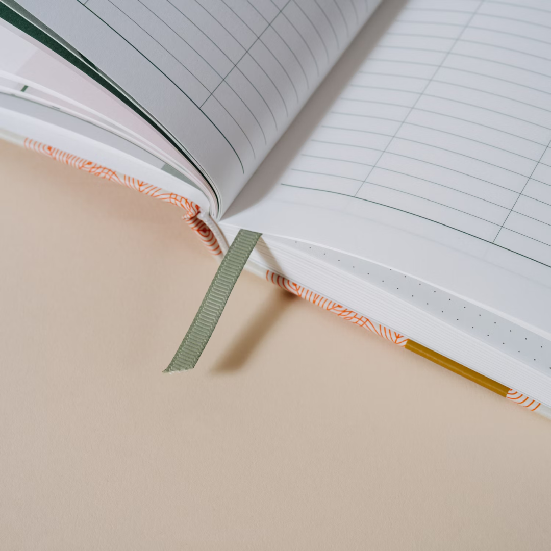 Close-up of the Papier Finance Planner Four Leaf open with its green ribbon bookmark