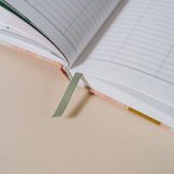Close-up of the Papier Finance Planner Four Leaf open with its green ribbon bookmark