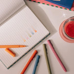 Papier High Energy Fineliners scattered on a desk with an open notebook