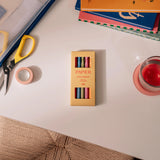 Papier High Energy Fineliners Set in its yellow box on a desk with scissors and tape