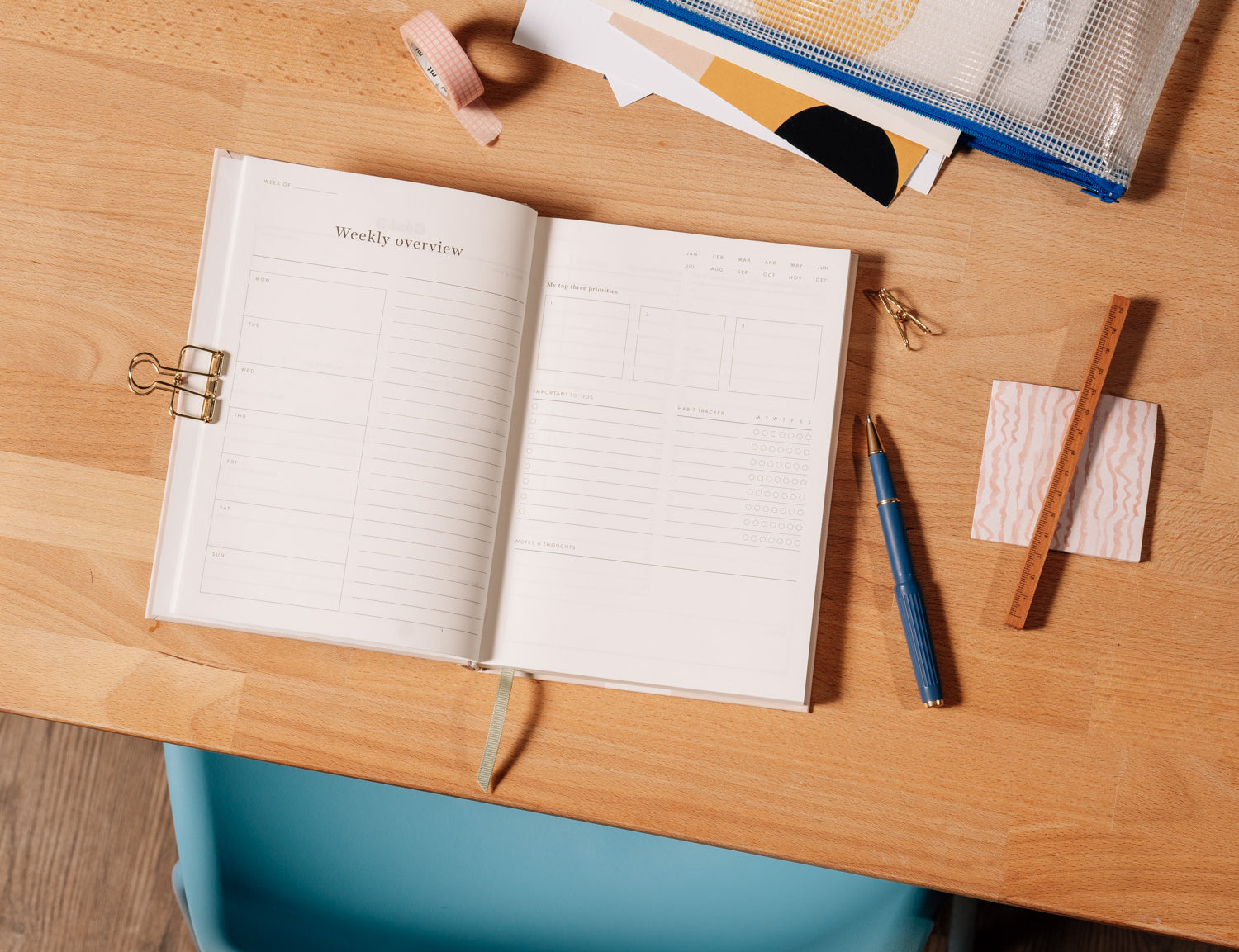 Papier Italian Summer Daily Productivity Planner open on a wooden desk with a pen and clips