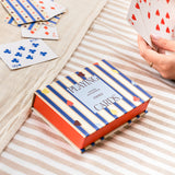 Hands playing a card game with Papier Playing Cards Suits & Stripes on a striped blanket