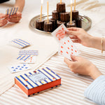 Papier Playing Cards Suits & Stripes on a picnic blanket with a tray of chocolate cakes