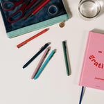 Papier Quintet Fineliners scattered on a desk with a pencil case and gratitude journal