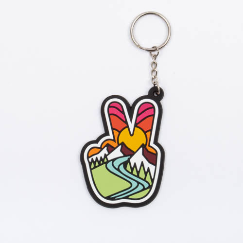 Peace sign keychain, a hand making a peace sign filled with a sunburst, snowy mountains and a green river valley, on a silver split ring.