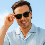 Peepers 18th Hole Sunglasses in dark green worn by a smiling man in a light blue shirt outdoors