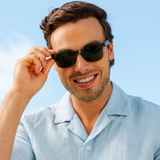 Peepers 18th Hole Sunglasses in dark green worn by a smiling man in a light blue shirt outdoors