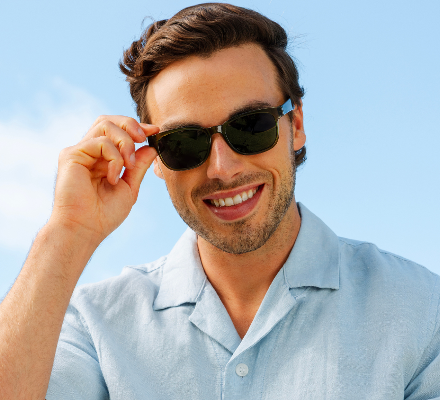 Peepers 18th Hole Sunglasses in dark green worn by a smiling man in a light blue shirt outdoors