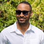 Peepers Airplane Mode Sunglasses in black worn by a smiling man in a white shirt outdoors