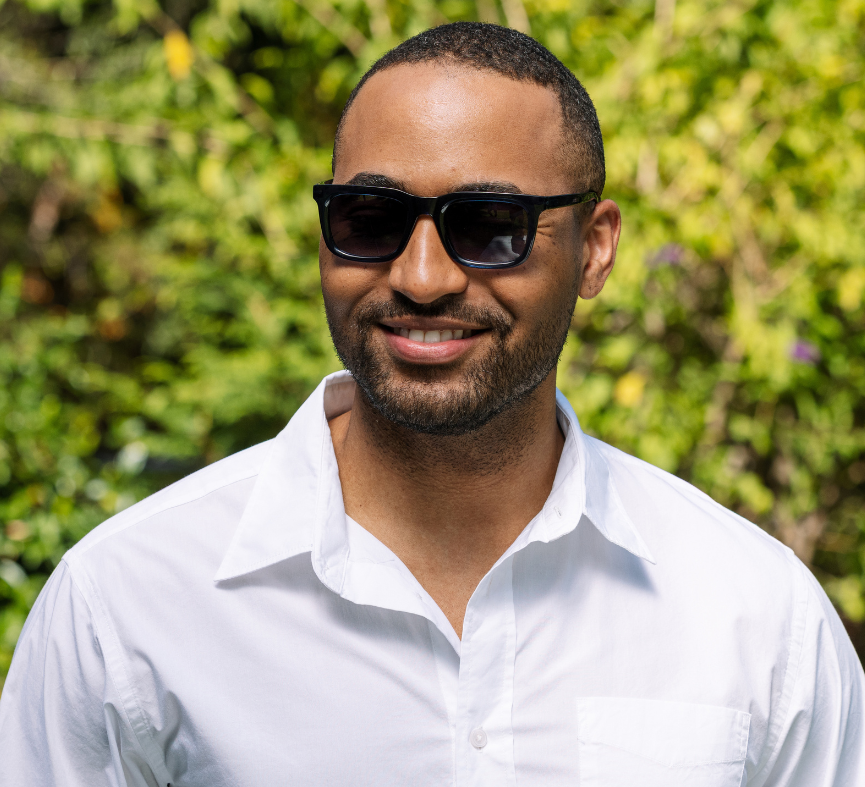 Peepers Airplane Mode Sunglasses in black worn by a smiling man in a white shirt outdoors