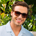 Peepers Airplane Mode Sunglasses in tortoise worn by a smiling man in a light blue shirt outdoors
