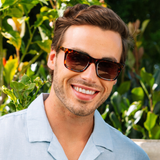 Peepers Airplane Mode Sunglasses in tortoise worn by a smiling man in a light blue shirt outdoors